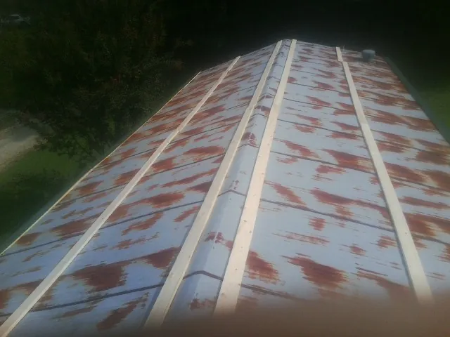 Rusted metal roof panels with new wood purlins before replacement — Storm Damage Roof Repair in New Sharon by Roofing Brothers