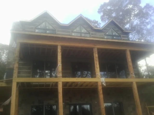 Dormers and porch framing on a large log home under construction — Roof Coating work by our crew in New Sharon