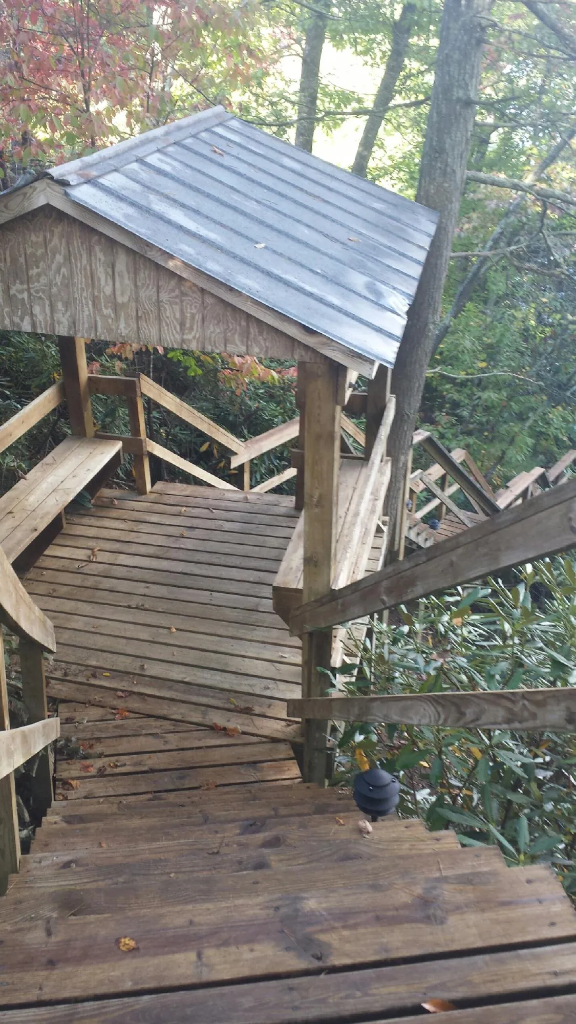 Metal roofed shelter over wooden steps on a wooded walkway — Skylight Repair & Installation work by our crew in New Sharon