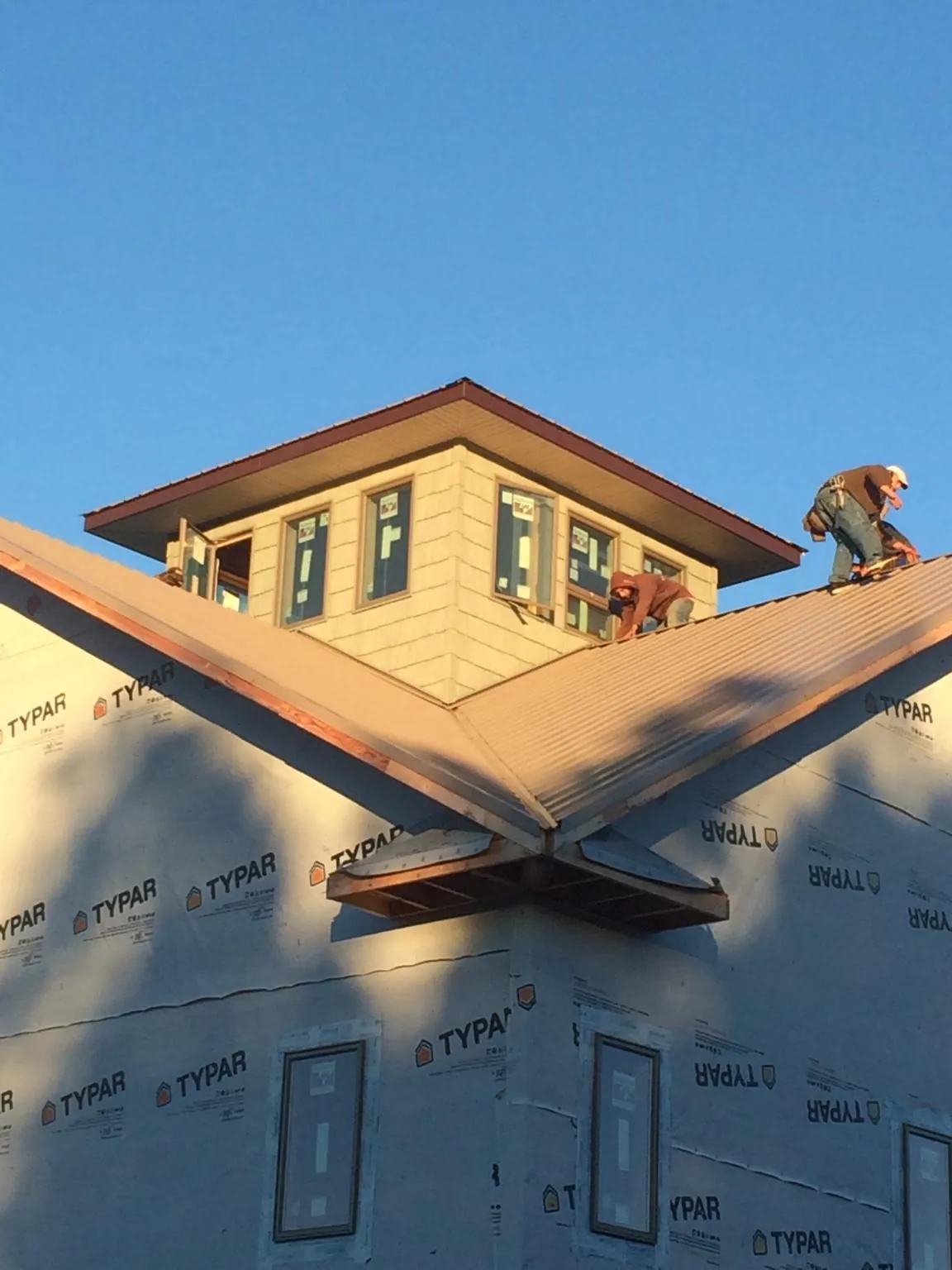 Roofers working around a rooftop cupola on a new metal roof at sunset — Roof Waterproofing in New Sharon by Roofing Brothers